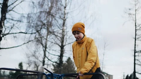 A boy in an orange jacket rides a carousel in the Park 動画素材 126731993
