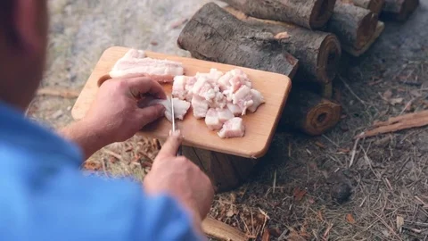 Boy outdoors bacon cut into cubes for cooking Stock Footage 76195793