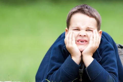 Boy outdoors without upper two teeth with pain in the face Stock Photos