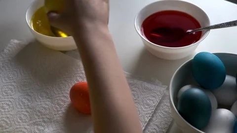 A boy painting an Easter egg on a white table. Colorful easter eggs. Easter Stock Footage 233039378