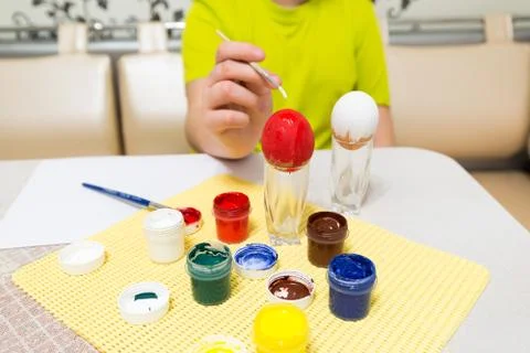 Boy paints  and brush easter eggs Stock Photos