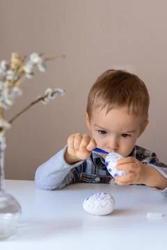 The boy paints decorative eggs for Easter with felt-tip pens Foto stock