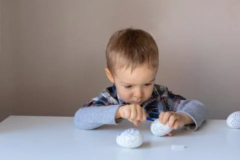 The boy paints decorative eggs for Easter with felt-tip pens Stock-Fotos