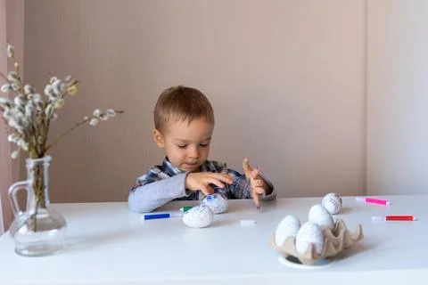 The boy paints decorative eggs for Easter with felt-tip pens Foto stock
