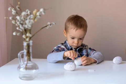The boy paints decorative eggs for Easter with felt-tip pens Fotos Stock