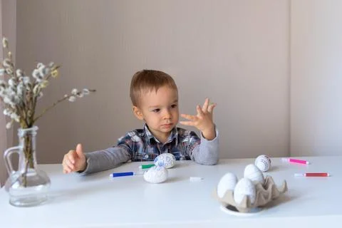 The boy paints decorative eggs for Easter with felt-tip pens Foto stock