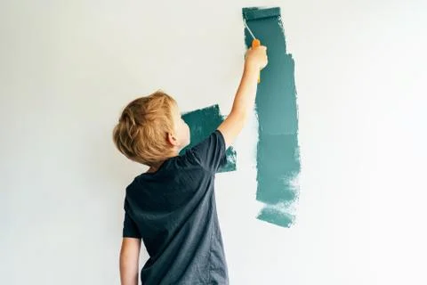 .boy paints a wall with a roller Stock Photos