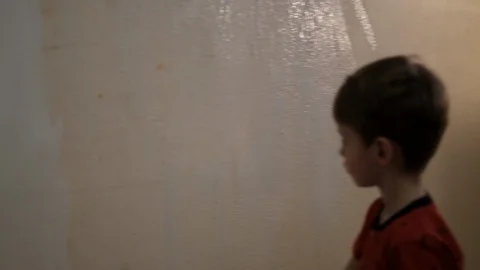 Boy paints a wall with white paint with a brush. Video picture. Shot from behind 스톡 동영상 119979039
