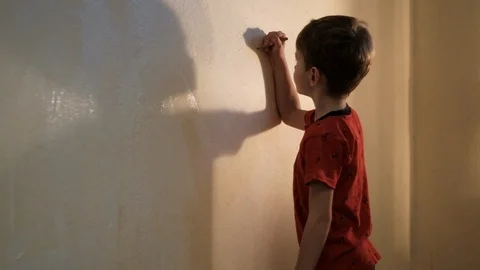 Boy paints a wall with white paint with a brush. Video picture. Shot from behind Stockbeeldmateriaal 119980574