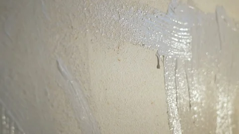 Boy paints a wall with white paint with a brush. Video picture. Shot from behind Stock Footage 119996506