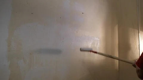 The boy paints the wall with white paint roller. Video picture. Shot from behind Stock Footage 119997241