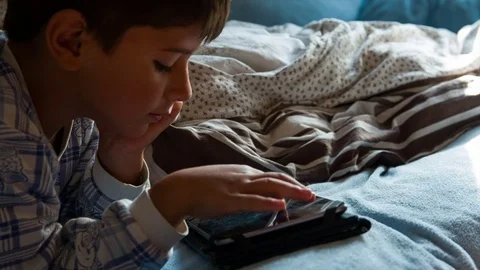 Boy in pajamas in bed playing Stock Footage 75614299
