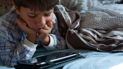 Boy in pajamas in bed with tablet smiles Stock-Footage 75614448