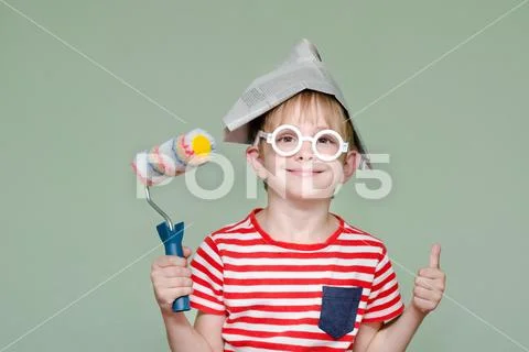 Boy in a paper hat and glasses shows the cool. Portrait. Roller for painting Stock Photos