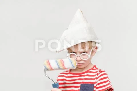 Boy in a paper hat is playing in a painter. Portrait. Roller for painting Stock Photos