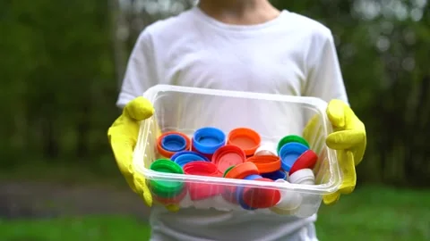A boy in the park holds plastic colored lids in a plastic container Stock Footage 160690758