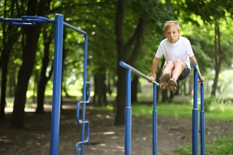 Boy in the park on horizontal bars Stock-Fotos