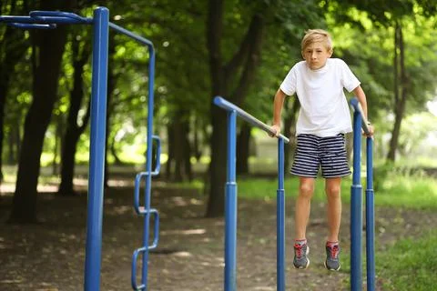 Boy in the park on horizontal bars Stock Photos