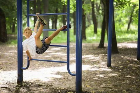 Boy in the park on horizontal bars Stock Photos