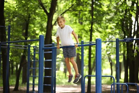 Boy in the park on horizontal bars Stock Photos