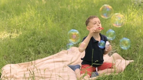 Boy in the park playing with soap bubbles Video stock 76161916