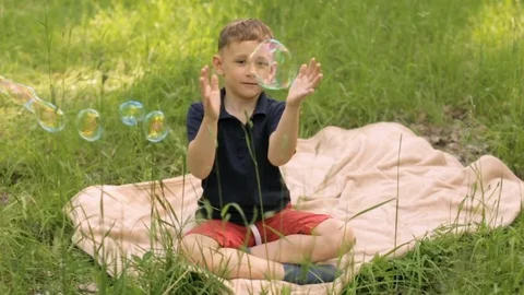 Boy in the park playing with soap bubbles Stock Footage 76162119