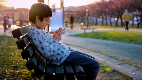 Boy in park on smartphone Stock Footage