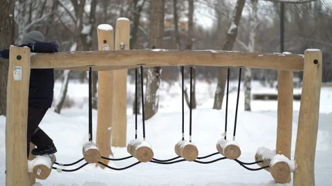 Boy passing obstacle course attraction in playground in winter. Stock Footage 233741001