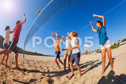 Boy passing volleyball during game on the beach Stock Photos