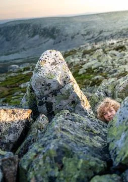 Boy Peeking From Behind Rocks While Playing Hide and Seek in Sweden Stock Photos