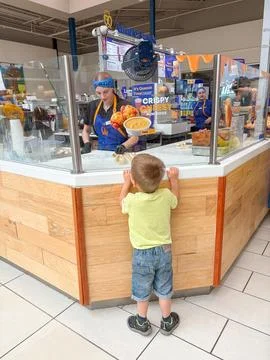 A boy peeks behind the shop window at the women working. - June 20, 2026, Fed Stockfoto's
