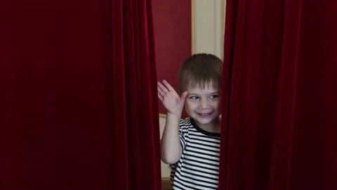 A boy peeks out from behind the stage curtain Stock-Footage 220603678