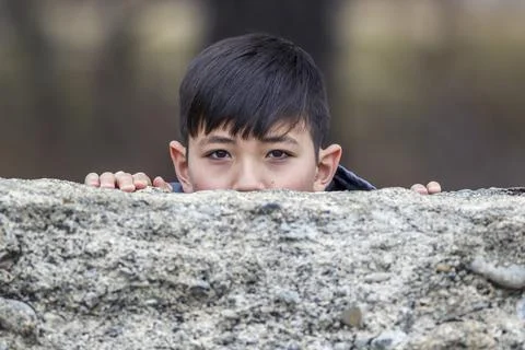 Boy peeks out from behind wall. Stock Photos