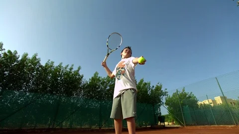 Boy performing a serve while playing tennis in slow motion Stock Footage 81231547