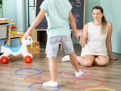 Boy performs exercises and steps into center of circle outlined by plastic ring Stock Photos