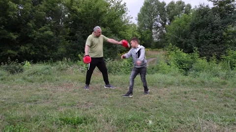 The boy performs a kick to a pad, developing strength and coordination during ac Stockbeeldmateriaal 327224018