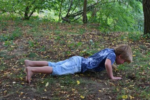 The boy performs a strength exercise in the forest. Foto stock