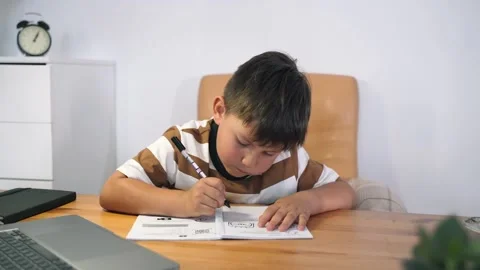 A boy performs a task in an online lesson. The child communicates online while Stock Footage 156748823