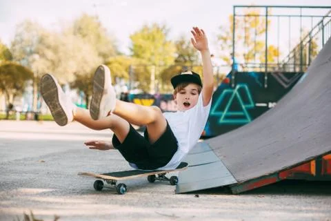 A boy performs tricks on a skateboard in a special area in the Park. A boy falls Stock Photos