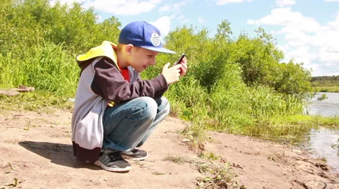 Boy with phone at the riverside Stock Footage 51298307