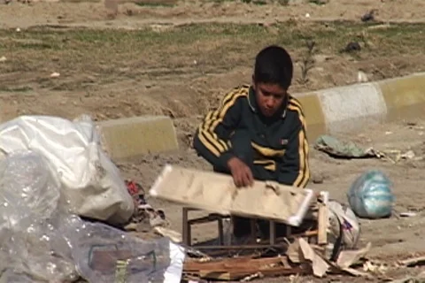 Boy picking bits of wood from pile of trash at the side of the road. Stock Footage 86753734