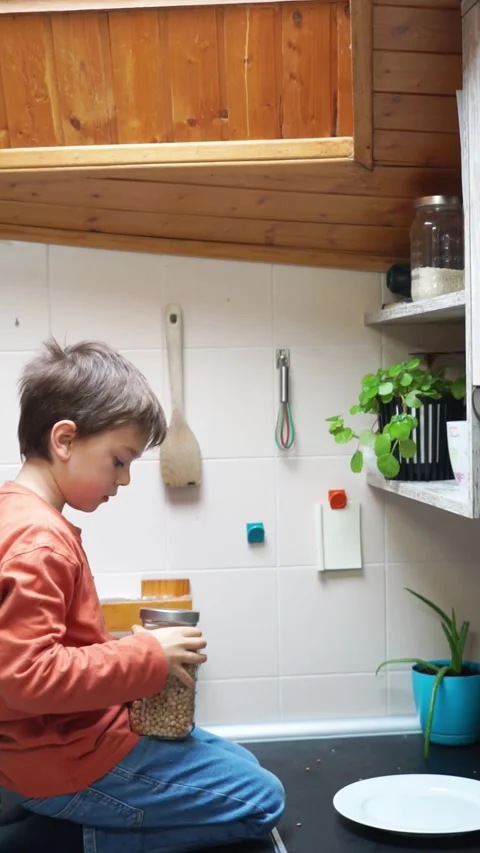 Boy picking up a glass jar from a kitchen shelf Stock Footage 270152689