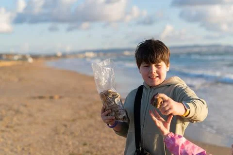 Boy picking shells on sea beach in autumn Stock Photos