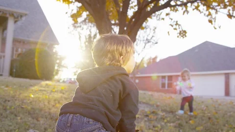 Boy picks up and throws leaves at sunset with lens flare Stock Footage 93887257