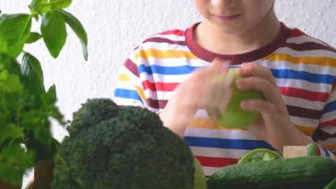 The boy picks up an apple. green vegetables and fruits Stock Footage 223108544