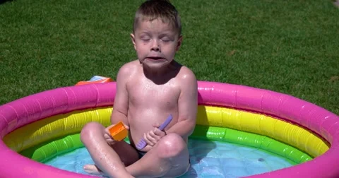 Boy Play and Having Fun in Inflatable Pool on Green Lawn in a Sunny Day Vidéo 65781553
