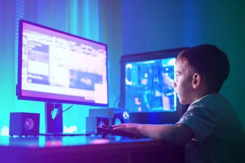 Boy play game on gaming computer or hacking a website concept. Dark scene wit Stock Photos