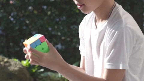 Boy play rubic cube in a garden Stock Footage 103970907