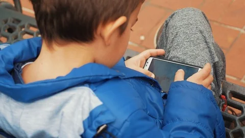 Boy play smartphon while sitting on the bench Stock-Footage 86189651