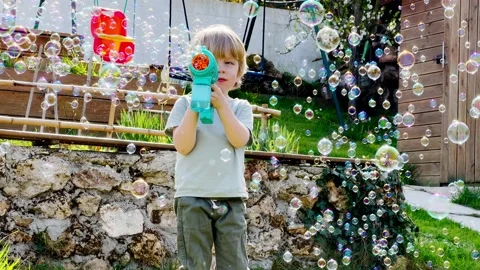 Boy play with soap bubbles holding bubble gun it the playground Stock Footage 211404342